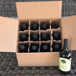 Open box of 12 olive oil bottles from above with a single bottle beside the box at the right, on a textured surface