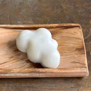 Nestled in a wooden soap dish is a single small cloud of soap. 