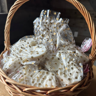 Wicker basket containing white soaps, packaged in gold polka-dotted cellophane party bags 